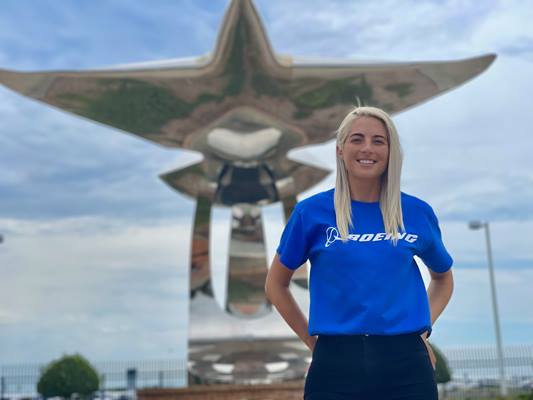 Photo of Vanesa Miska infront of aviation statue wearing blue Boeing shirt