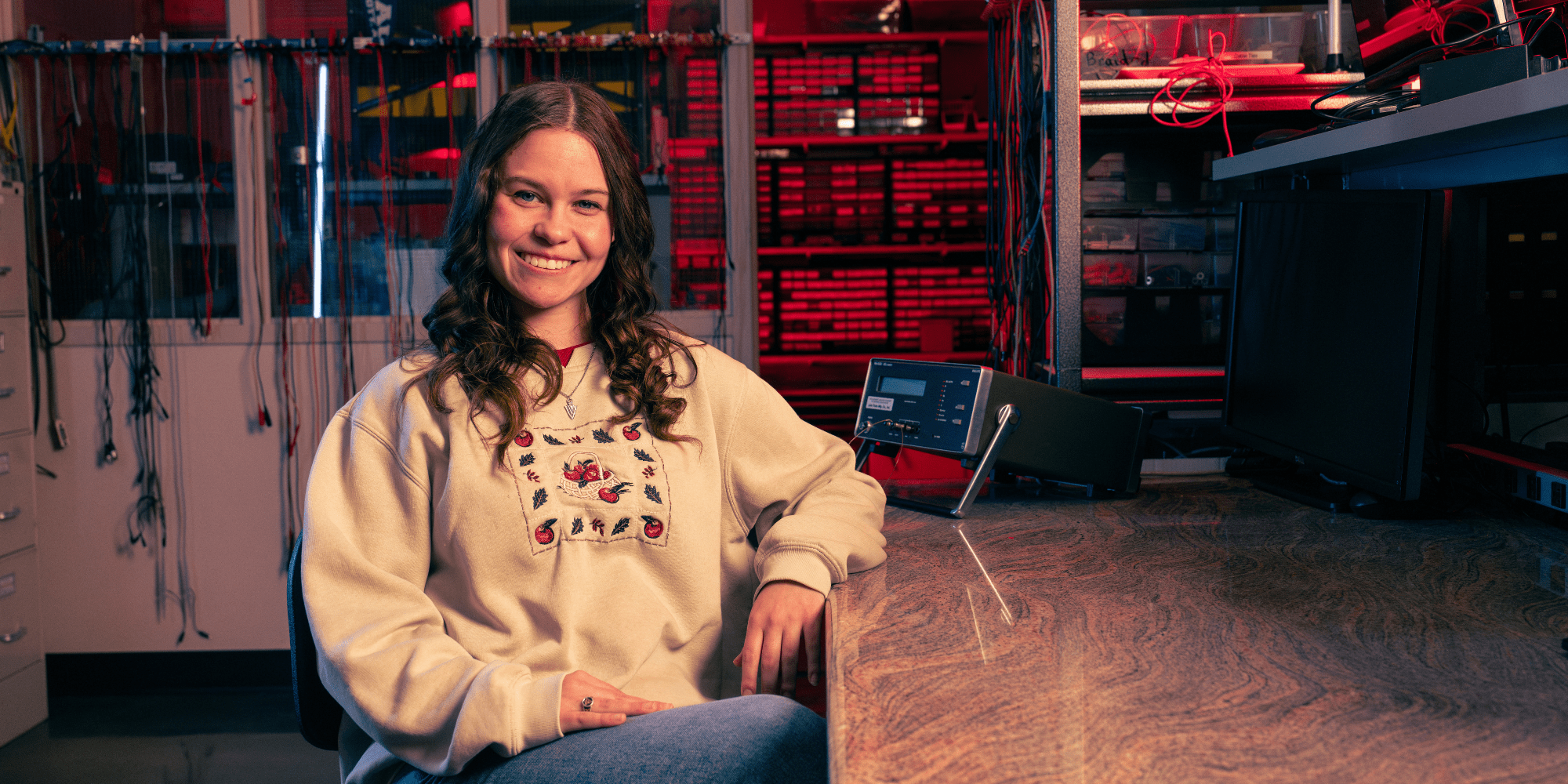 Molly, sitting down and smiling in a tan sweatshirt.